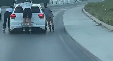 Otomobile tutunarak ilerleyen patenli çocuklar kamerada